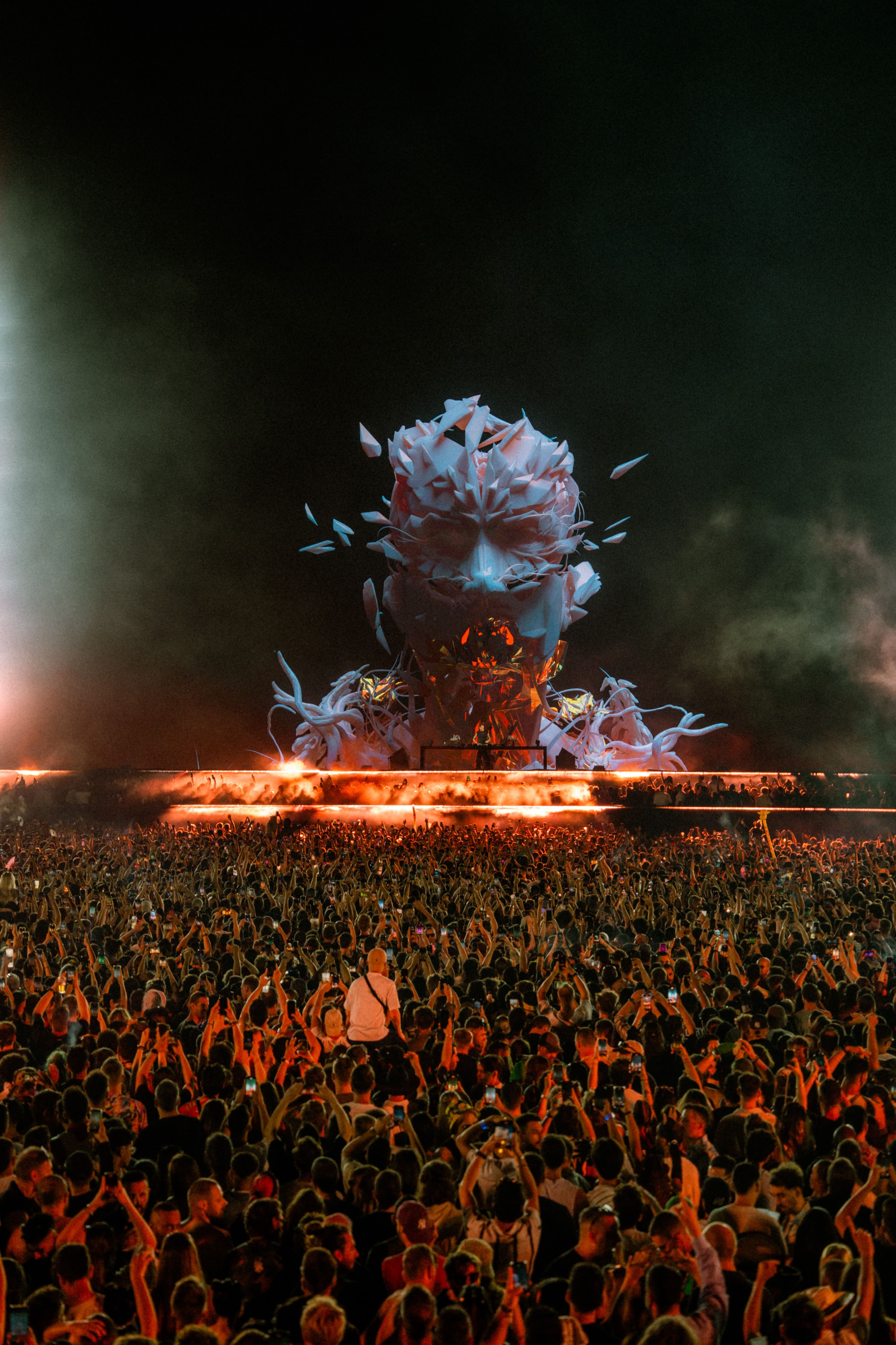 A crowd facing a lit stage at a night concert