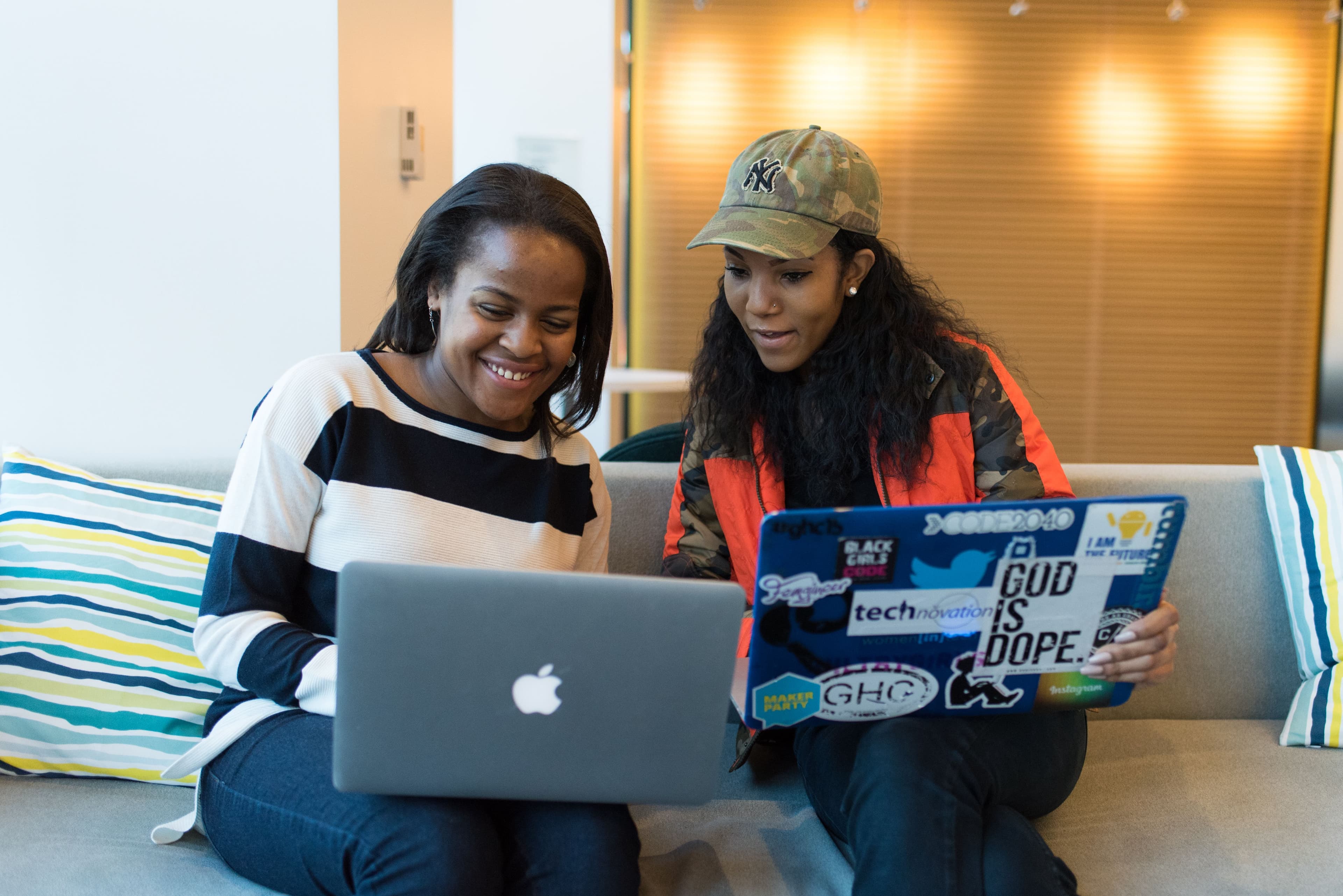 Two colleagues sitting together with laptops in an office