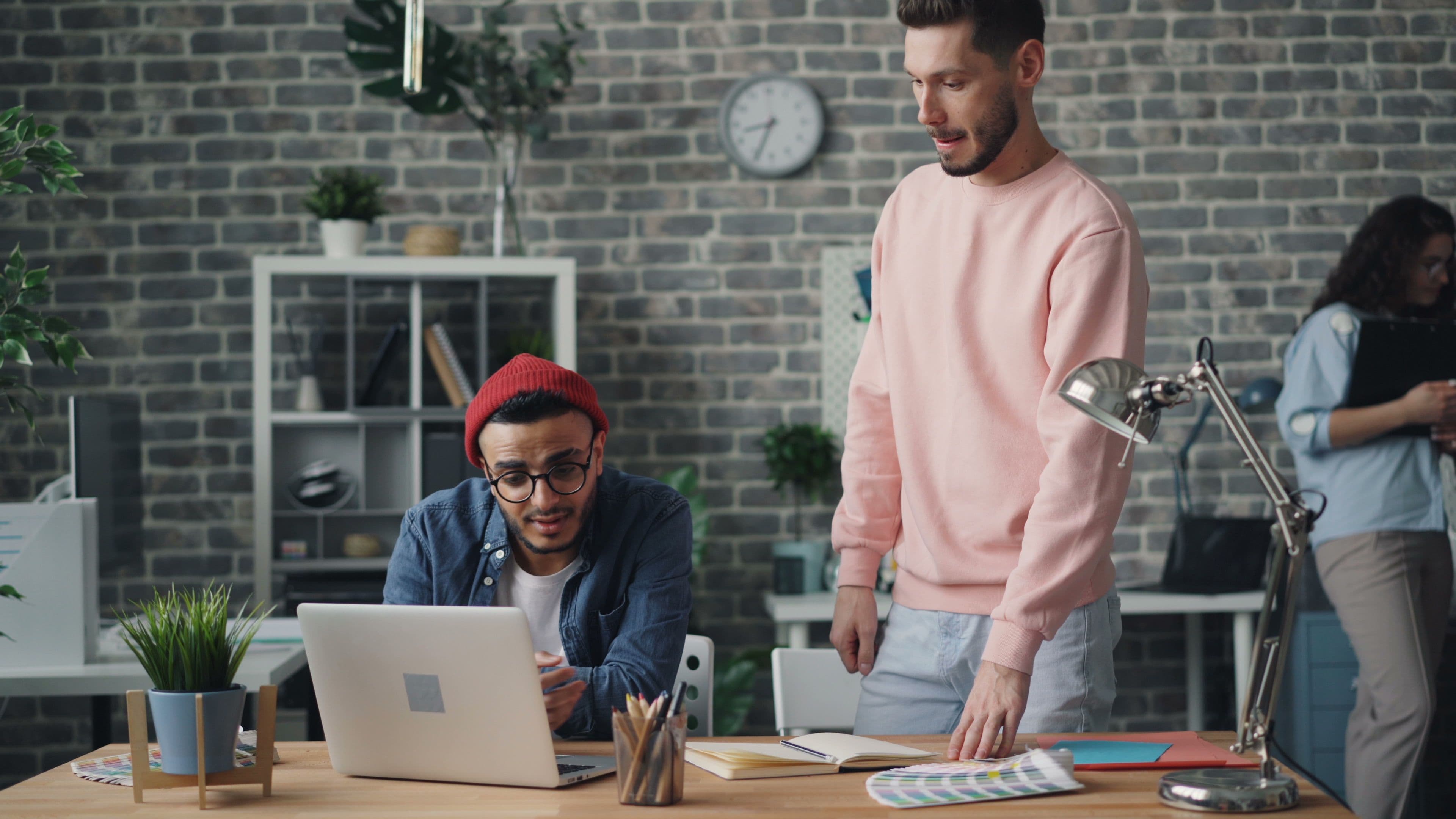 Two colleagues looking at a laptop on a shared desk