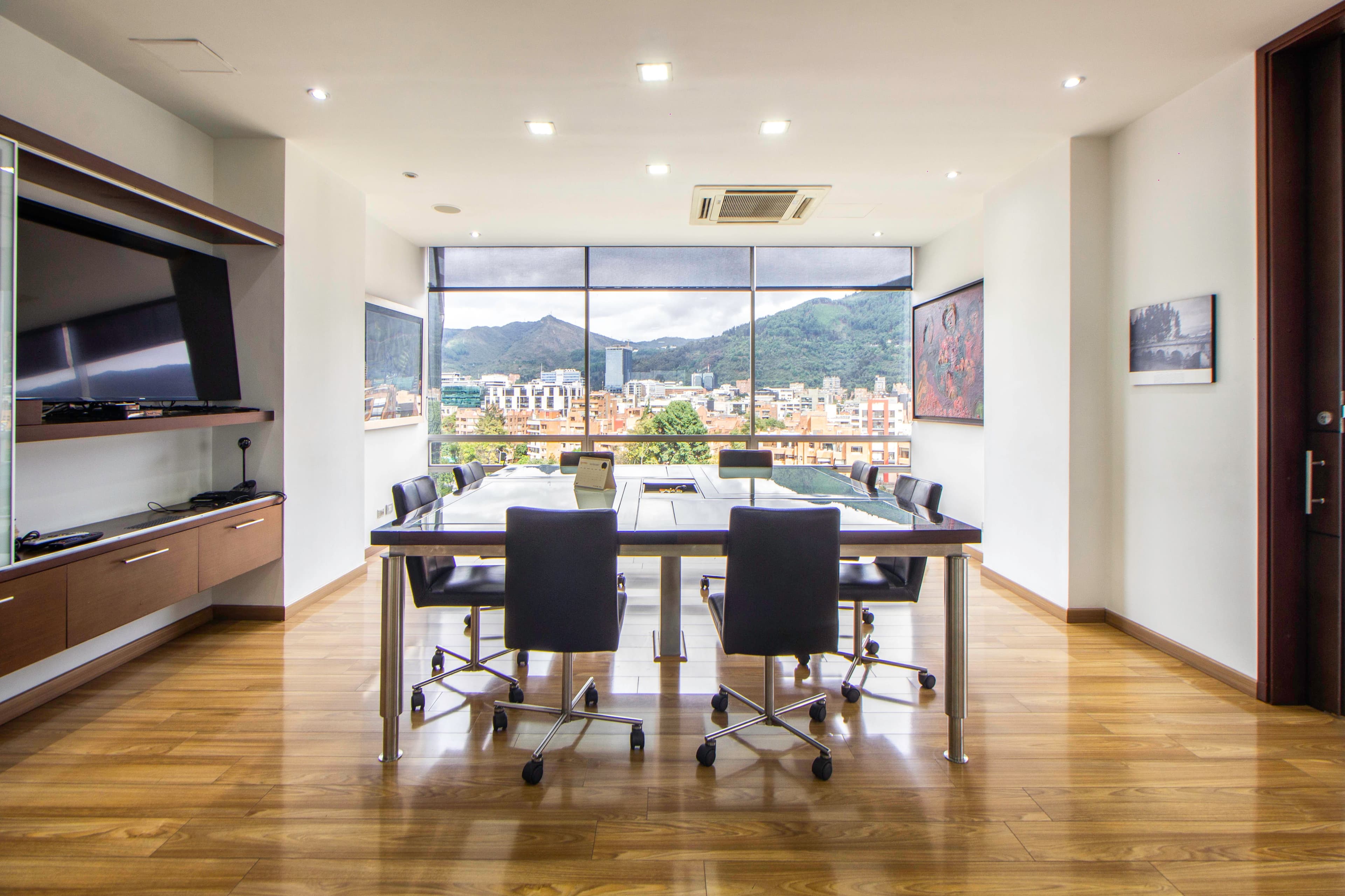 An empty boardroom with a glass table and a city view